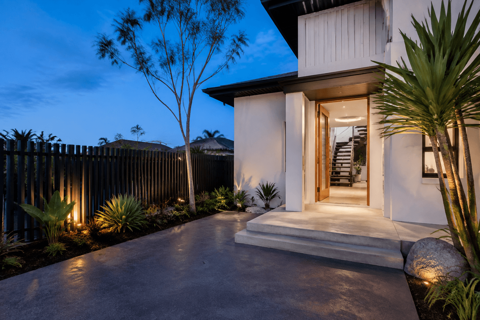 Concrete entrance and wide steps beside a modern home at dusk